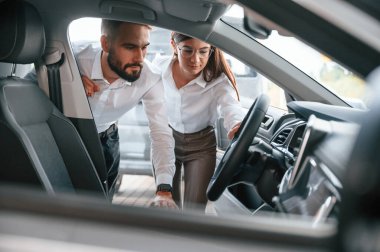 Otomobil salonunu kontrol ediyorum. Beyaz elbiseli bir adam araba galerisinde birlikte..