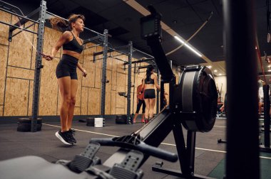 Sportif kadın atlama ipi kullanarak spor salonunda egzersiz yapıyor..