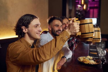 Bardakları kaldırıyorum. Üç arkadaş barda bira içip iyi vakit geçiriyorlar..