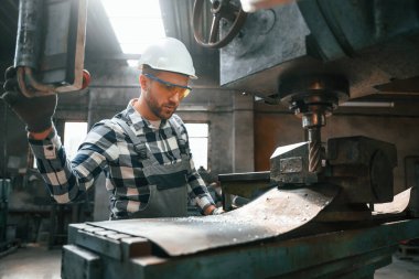 Otomatik matkabı çalıştırıyorum. Üniformalı fabrika çalışanı içeride..