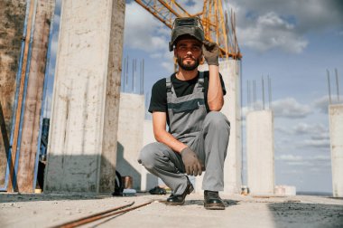 Kaynak maskesiyle. Üniformalı adam inşaat alanında çalışıyor..