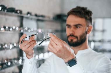 Büyük seçim. Optik mağazasından gözlük seçen sakallı şık bir adam..