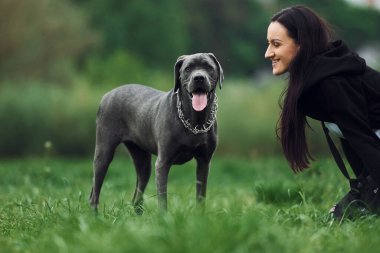Genç esmer kız köpeğiyle dışarıda yürüyüş yapıyor..