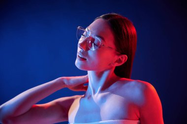 Gözlüklü, kötü görüş anlayışı. İçerideki neon ışıkta duran genç bir kadının portresi..