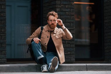 Kaldırımda oturuyordum. Sakallı, haki renkli ceketli ve kot pantolonlu şık bir adam binanın yanında..