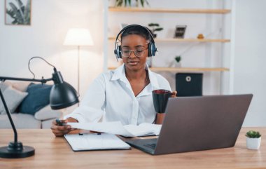 Serbest çalışan biri. Beyaz gömlekli Afro-Amerikan kadın evde..