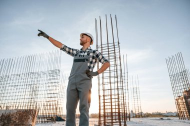 Eller yukarı. Emirleri vermek. Gündüz vakti inşaatta çalışan bir adam var..