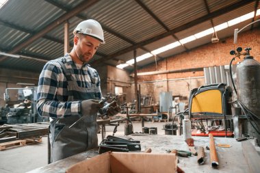 Profesyonel aletleri kullanarak. Üniformalı fabrika çalışanı içeride..