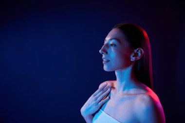 Yan görüş. İçerideki neon ışıkta duran genç bir kadının portresi..