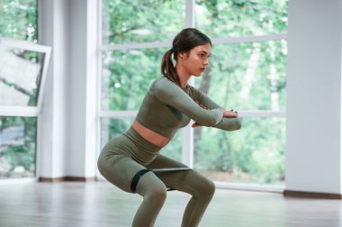 Çömeliyor. Spor elbiseli kadın spor salonunda spor günü düzenliyor..