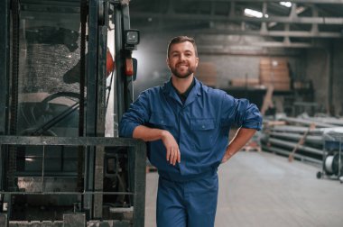 Forklifte yaslan. Mavi üniformalı fabrika işçisi içeride..
