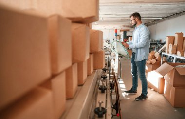 Makine operatörü bir cihaz kurmakla meşgul. Beyaz elbiseli matbaacı içeride..
