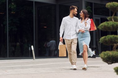 Modern binanın yanında yürüyorum. Güzel bir çift gün içinde dışarıda alışveriş yapar..