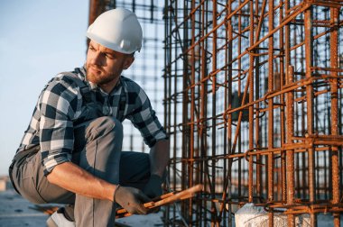 Paslı metal nesnelerle. Gündüz vakti inşaatta çalışan bir adam var..
