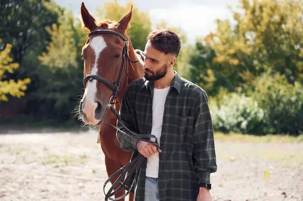 stock image Front view. Young man with a horse is outdoors.