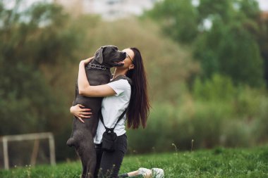 Evcil hayvana sarılıyor. Genç esmer kız köpeğiyle dışarıda yürüyüş yapıyor..