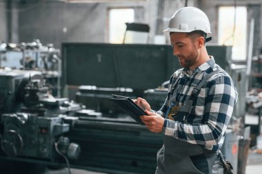 Siyah renkli grafik tablet tutuyordu. Üniformalı fabrika çalışanı içeride..