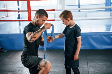 Boks kıyafetlerini giymişsin. Koç antrenman alanında oğlanla birlikte..