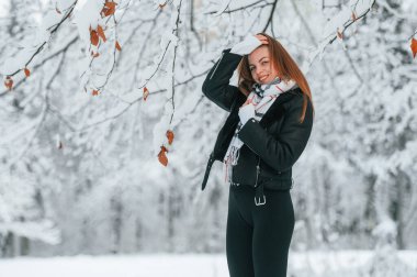Durup poz vermek. Güzel genç bir kadın kış ormanında dışarıda..
