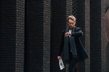 Kontrol zamanı. Sakallı ve gözlüklü şık adam binanın yanında..