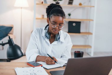 Serbest çalışan biri. Beyaz gömlekli Afro-Amerikan kadın evde..