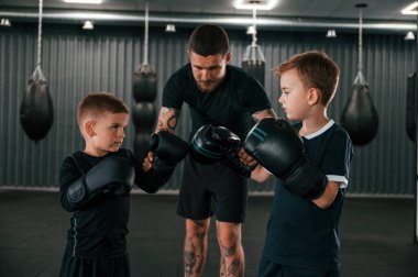 Antrenman için hazırlanıyorum. Genç dövmeli koç çocuklara boks teknikleri öğretiyor..