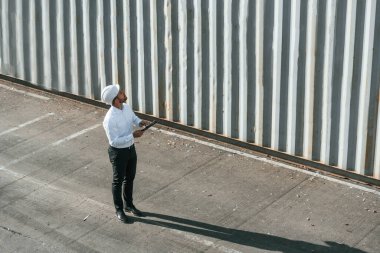 Üst Manzara. Tabletle. Erkek işçi konteynırlarla birlikte olay yerinde..