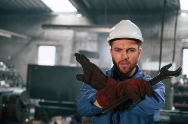 El hareketi. İngiliz anahtarıyla. Mavi üniformalı fabrika işçisi içeride..