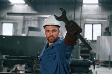 Anahtarı elinde tut. Mavi üniformalı fabrika işçisi içeride..