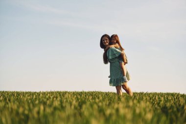 Gökyüzü açık. Anne ve kızı yazın açık havada eğleniyorlar..