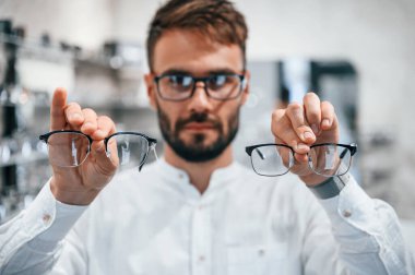 Modern görünüş. Optik mağazasından gözlük seçen sakallı şık bir adam..