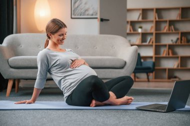 Laptop kullanarak yoga dersleri alıyorum. Güzel hamile kadın evde..