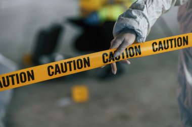 Dikkatli polis bandına yakından bak. Dedektifler cesedin yanındaki suç mahallinde kanıt topluyorlar..