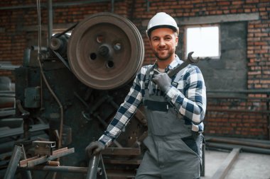 Elinde büyük bir anahtar var. Üniformalı fabrika çalışanı içeride..