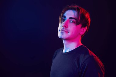 Feeling relaxed. Man standing in the studio with neon light.