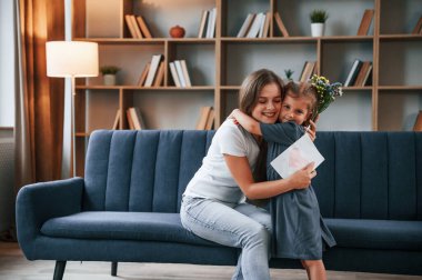 Birbirinize sarılın. Hediyeyi veriyorum. Genç anne kızıyla birlikte dairede..