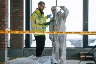 Gündüz vakti. Dedektifler cesedin yanındaki suç mahallinde kanıt topluyorlar..