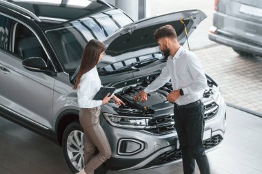 Kaput açıldı. Beyaz elbiseli bir adam araba galerisinde birlikte..