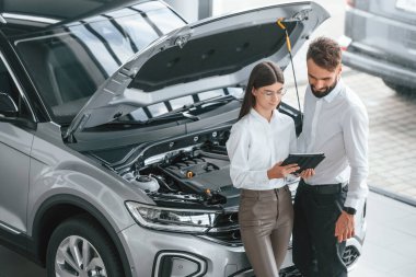 Kaputun altında ne var? Beyaz elbiseli bir adam araba galerisinde birlikte..