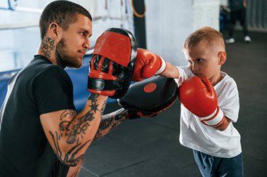 Öğrenme süreci. Elini yumruklamak. Koç çocuklara kapalı alanda boks teknikleri öğretiyor..