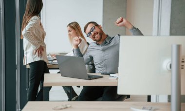 Gümüş renkli dizüstü bilgisayar masada. Ofiste başarılı bir ekip birlikte çalışıyor. İş kavramı.