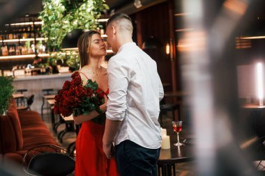 Adam güzel çiçekler veriyor. Romantik çift restoranda yemek yiyor..