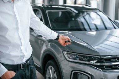 Otomobili uzaktan kumandayla kapatıyorum. Beyaz elbiseli genç adam araba galerisinde..