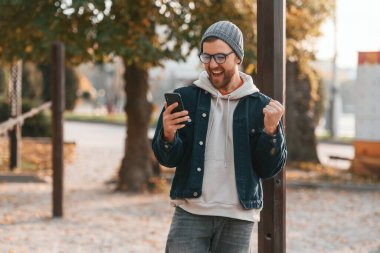 Hoş bir sürpriz. Akıllı telefonlu. Kalın elbiseli güzel adam dışarıda, parkta..