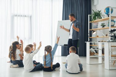 Beyaz tahtayı kullanarak. Okulda öğretmenle birlikte bir grup çocuk öğrenci..