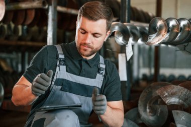 Müdür dijital tablet kullanıyor. Üniformalı adam iş yerinde tarım tekniğinin detaylarını geliştiriyor..