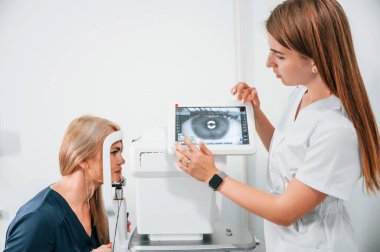 Yan görüş. Kadının görüşü özel bir cihaz kullanan klinik çalışanı tarafından test ediliyor..