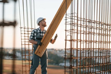 Adam gündüz vakti şantiyede çalışıyor. Büyük ahşap tahtayı hareket ettiriyorum..