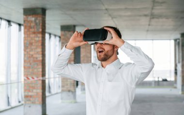 İnşaat alanında resmi kıyafetli bir adam VR oyunu oynuyor..
