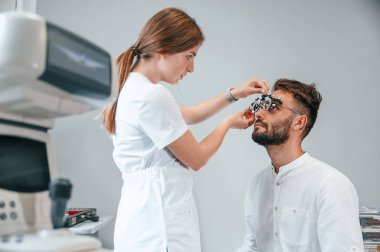 Optometrik cihaz. Klinikteki kadın doktor adamın görüşünü kontrol etti..